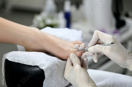 Master pedicure in white gloves make quality pedicure, removes the cuticle