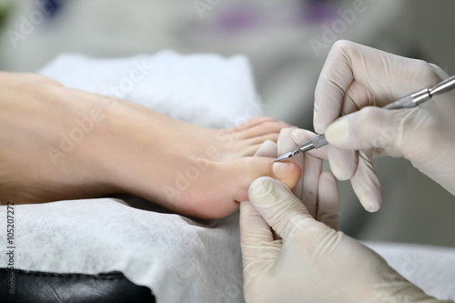 Close up photo of the foot on which the cuticle is removed. pedicure master