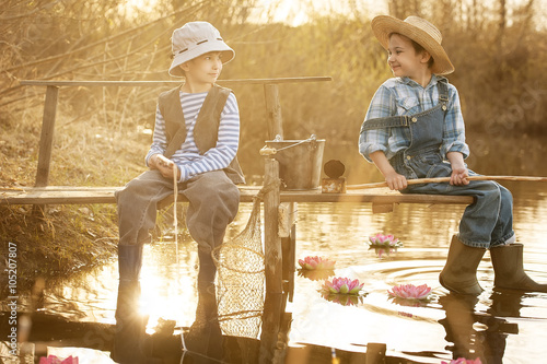 Boys fishes on a bridge on the lake