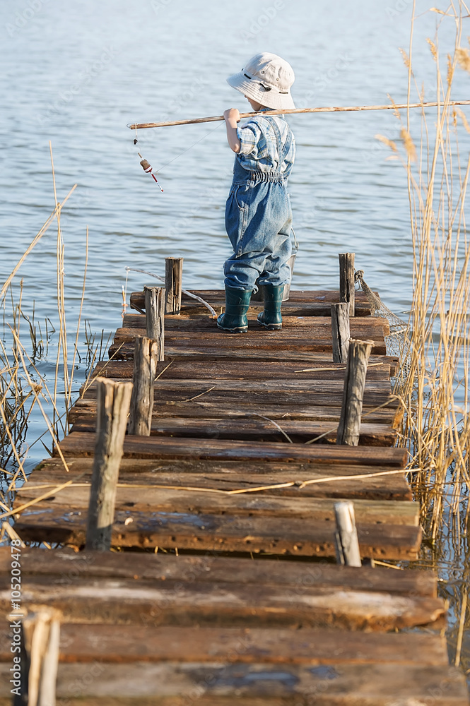 Boy fishes on a bridge on the lake Boy fishes on a bridge on the lake