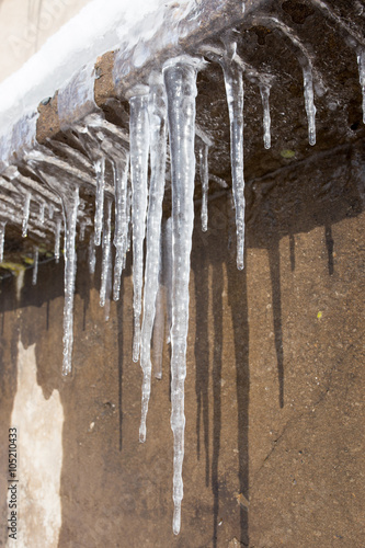 Large icicles hanging on the roof of the house in springtime