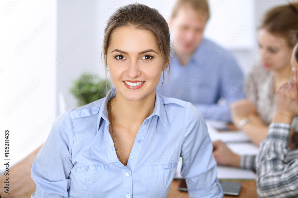 Beautiful business woman on the background of business people during meeting. Casual clothing style. Start up team.