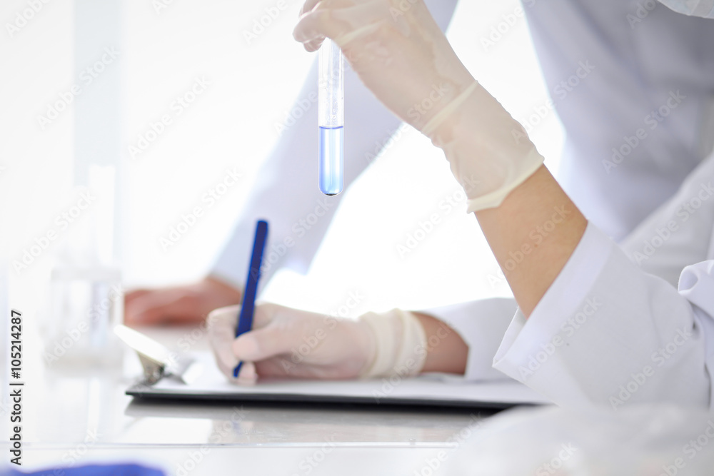 Scientific research team with clear solution in laboratory, close up Scientific research team with clear solution in laboratory, close up