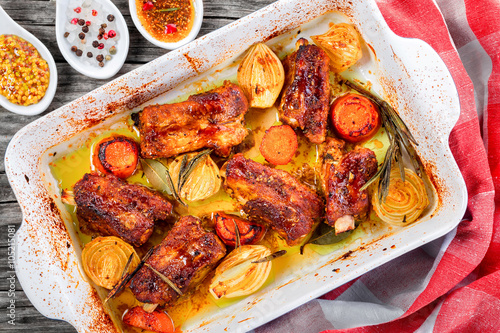roasted ribs in a baking dish with onion, carrots, spices