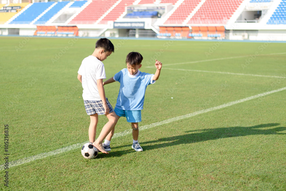 Fototapeta premium Boy play football on the lawn