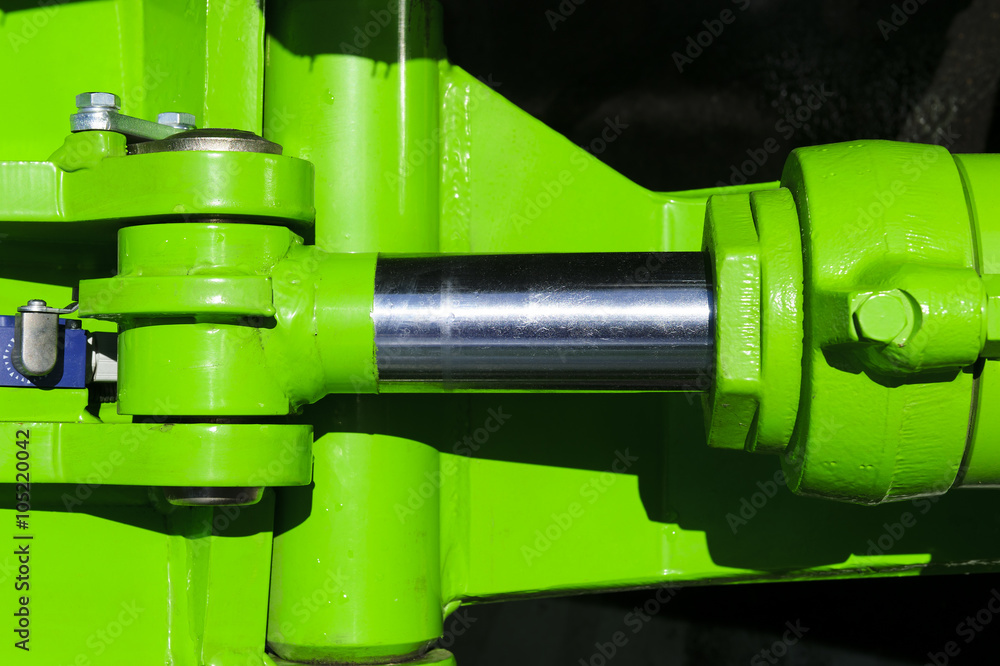 Obraz premium Hydraulic piston system for bulldozers, tractors, excavators, chrome plated cylinder shaft of green machine, construction heavy industry detail, selective focus 