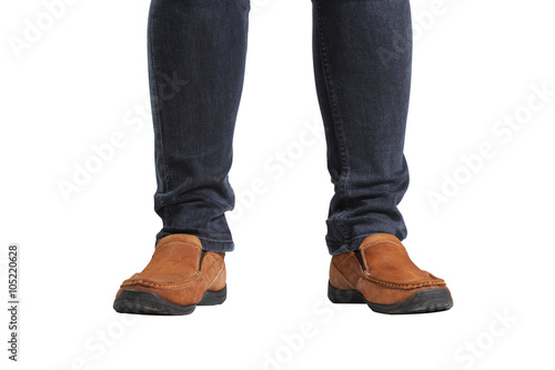 Young fashion man's legs in blue jeans and brown boots on white floor
