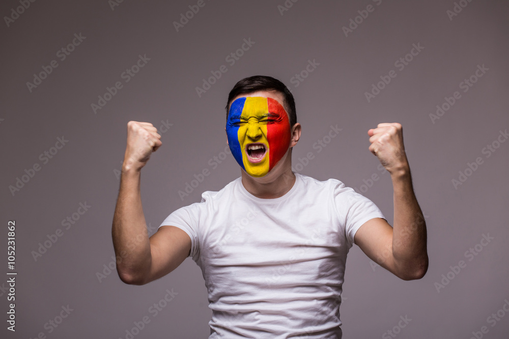Victory, happy and goal scream emotions of Romanian football fan in game support of Romania national team on grey background. European football fans concept. Victory, happy and goal scream emotions of Romanian football fan in game support of Romania national team on grey background. European football fans concept.