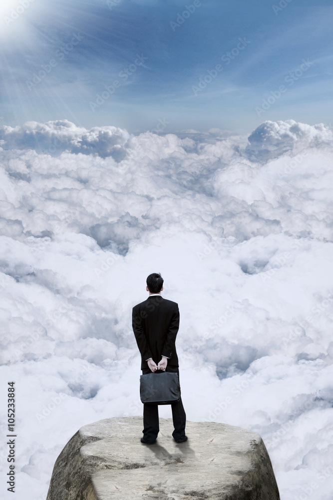 Businessman looking at clouds at mountain Businessman looking at clouds at mountain