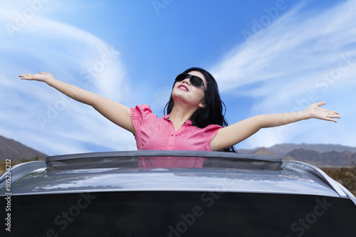 Cheerful woman standing on the sunroof © Creativa Images