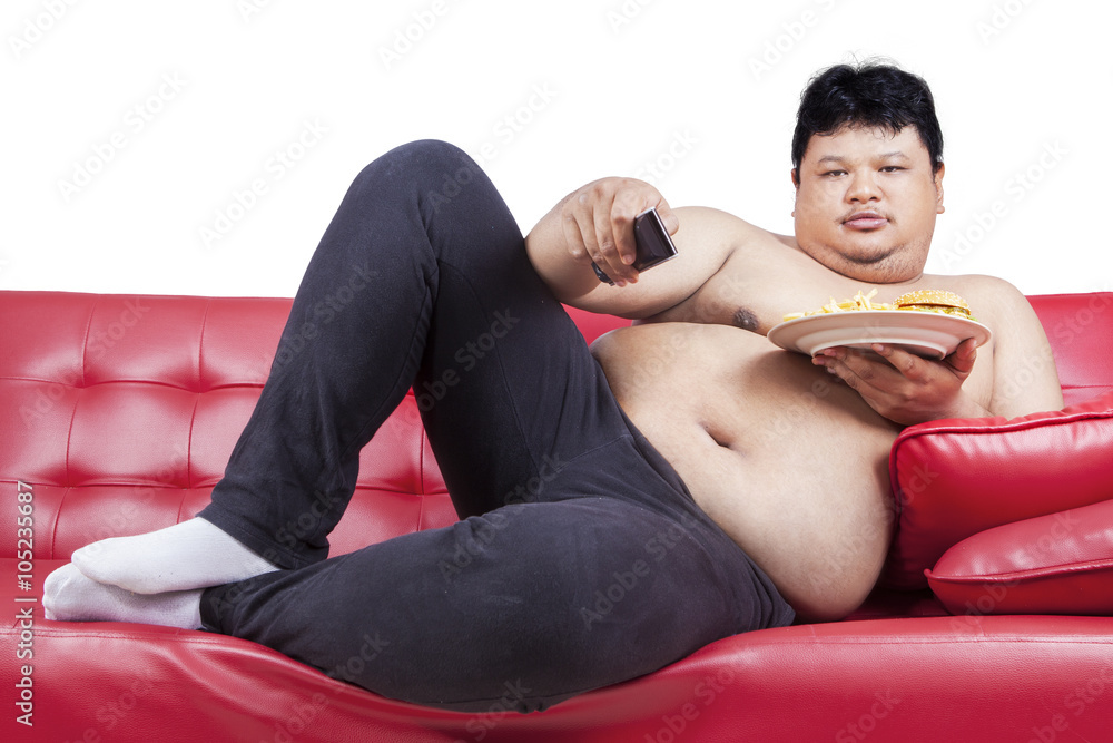 Obese man watching tv while holding burger Obese man watching tv while holding burger