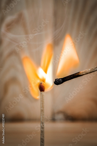 match is ignite on a blurry wood background. Selective focus.