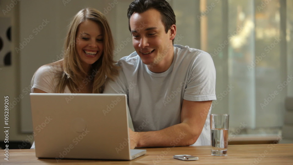 Couple in kitchen looking at laptop computer together Couple in kitchen looking at laptop computer together