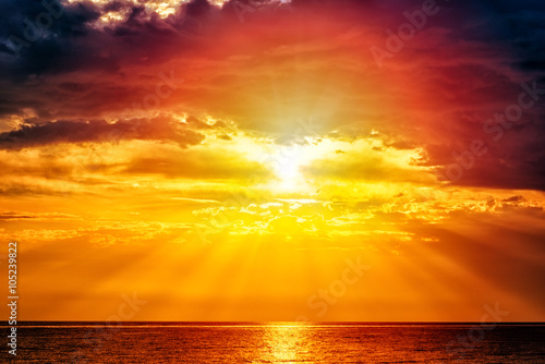 Fabulous seascape with sea and sky - yellow sun and deep red clouds above the water