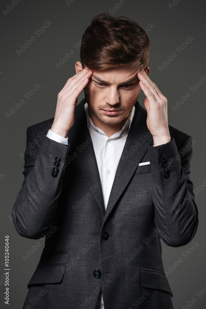 Upset unhappy businessman touching his temples and having a headache Upset unhappy businessman touching his temples and having a headache