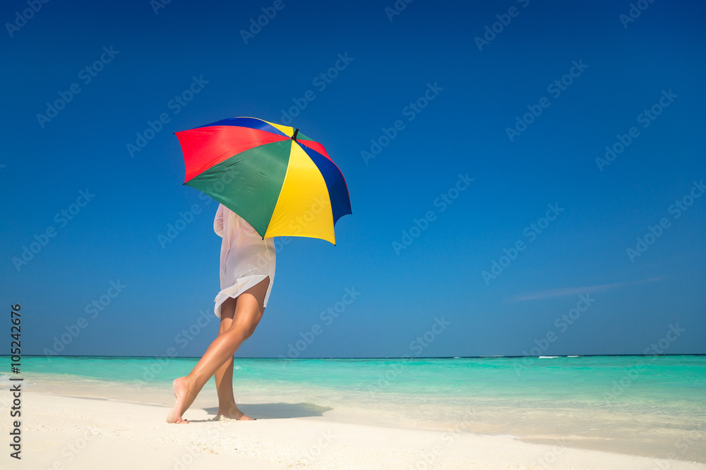 Girl with an colorful  umbrella on the sandy beach