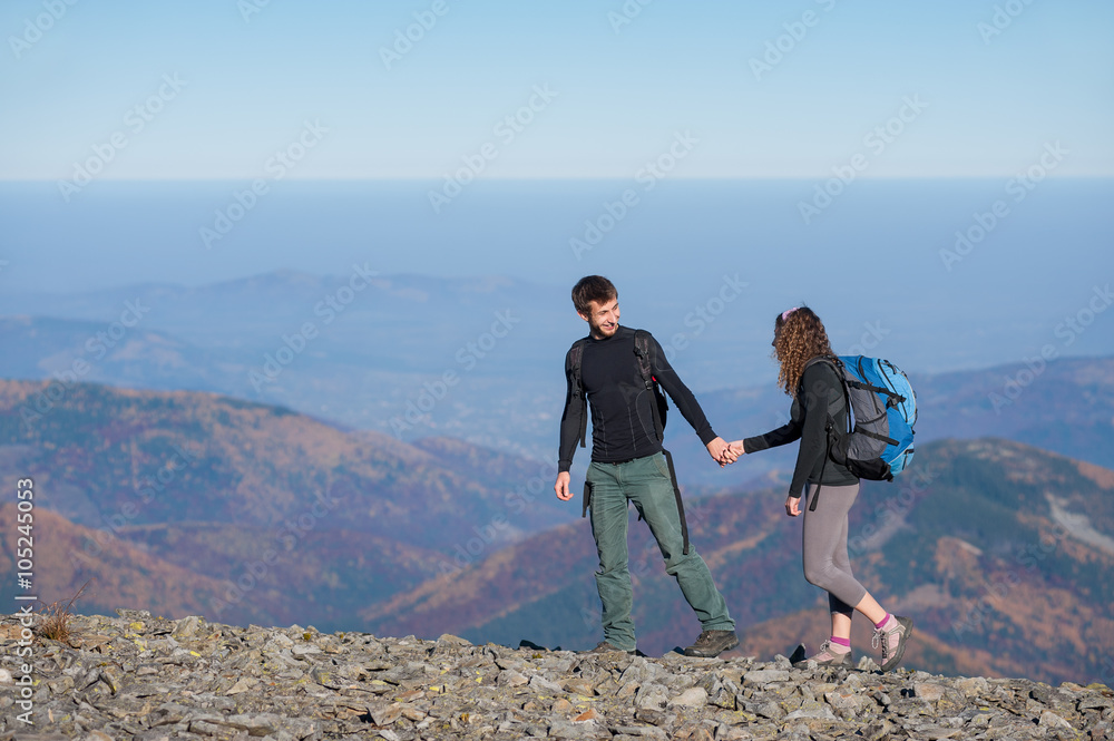 Young couple hikers climbing up with backpacks on the ridge of the ...