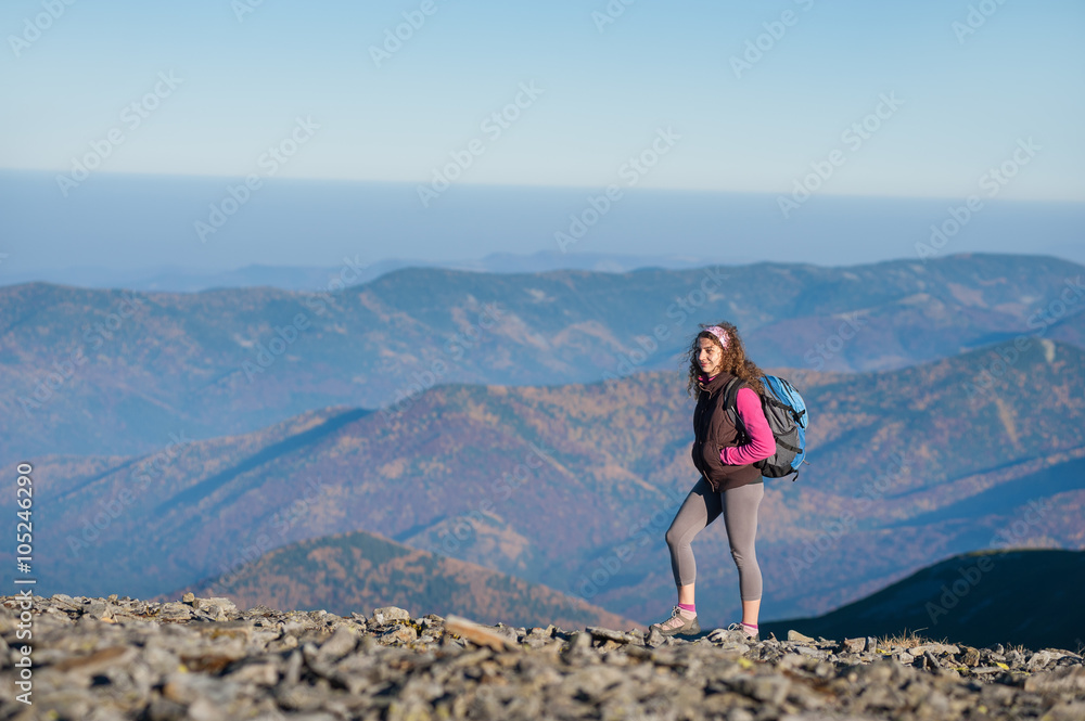 Young athletic girl backpacker walking on the ridge of the mountain enjoying the open view on the big mountains. Rear view, sunny fall day.