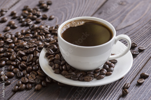Cup of coffee on wooden background with coffee beans
