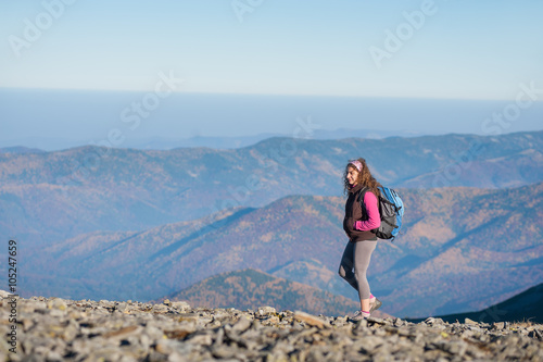 Young athletic female backpacker climbing on the ridge of the mountain enjoying the open view on the big mountains. Rear view, sunny autumn day.