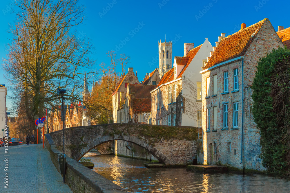 Scenic cityscape with a medieval tower Belfort, bridge and the Green canal, Groenerei, in Bruges in the morning, golden hour, Belgium