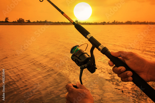 hand man fishing in river sunset background