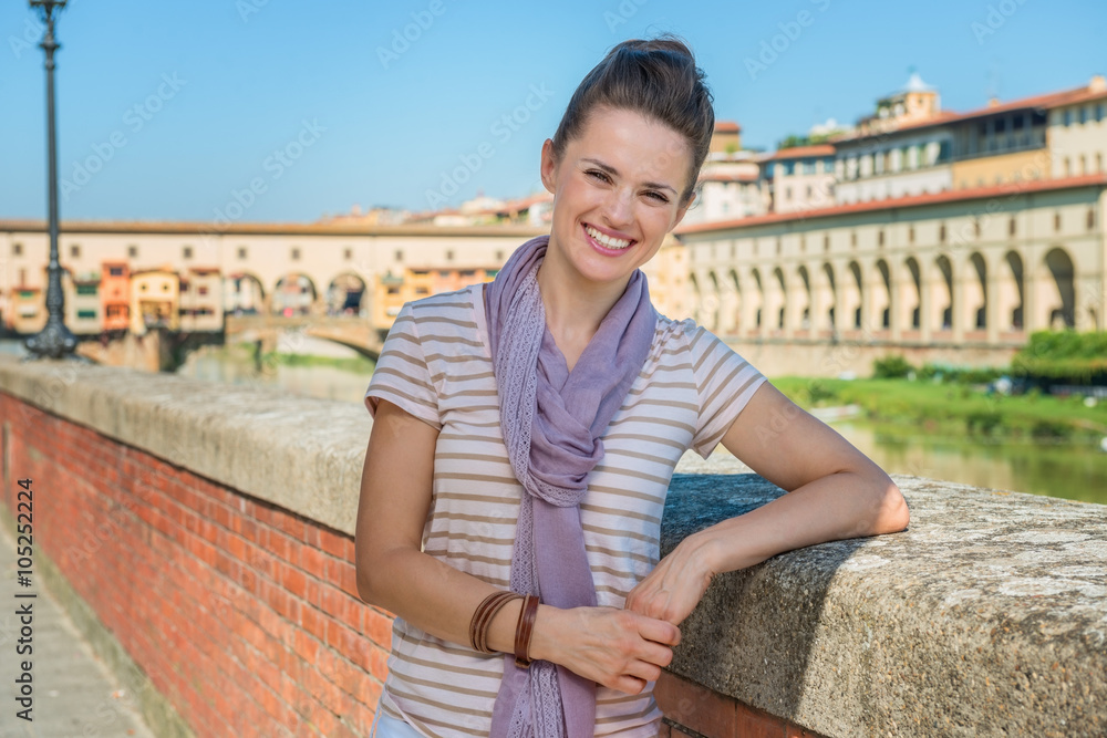 Smiling tourist standing on embankment overlooking Ponte Vecchio