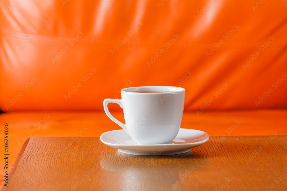 Obraz premium cup of tea on wood table with orange background
