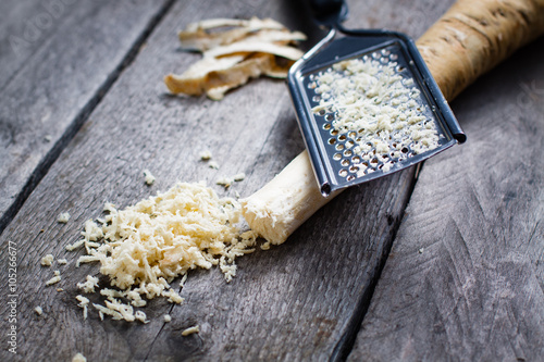 Canvas-taulu Grated horseradish root with grater on wooden gray table.