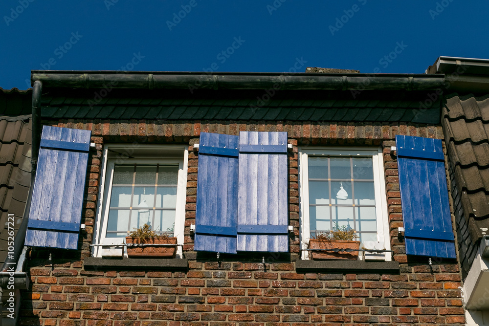 Altes Backsteinhaus mit blauen Fensterläden Altes Backsteinhaus mit blauen Fensterläden
