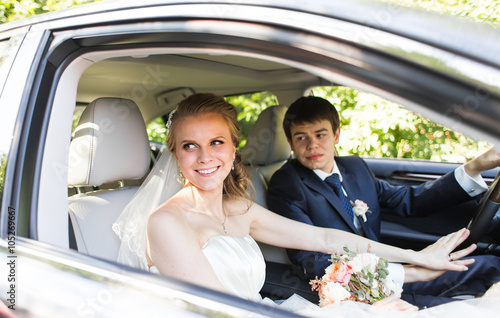 Bride and groom inside a car. They are happy.