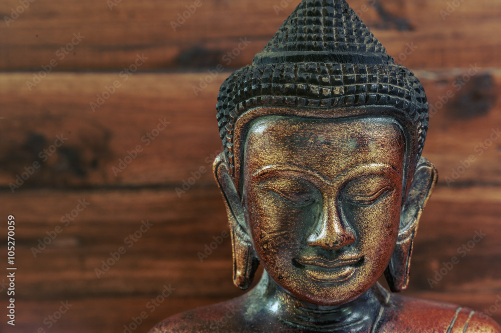 Wooden bronze buddha on wooden blurred background