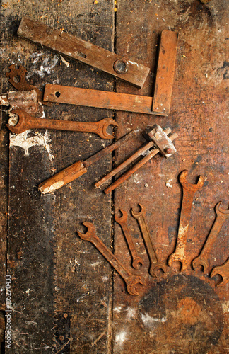 Old rusty wrench and other woodworking tools on dirty wooden table