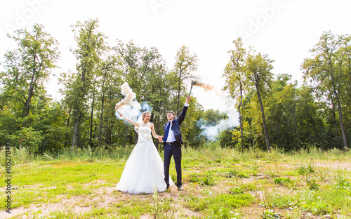 Wedding couple with color smoke in the summer park. © satura_