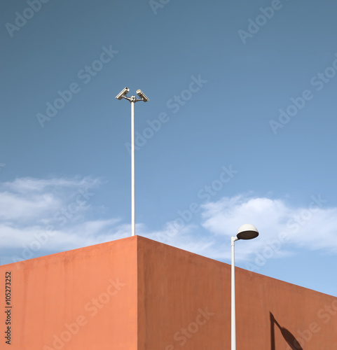Betonmauer - Fototapete Weisse Überwachungskameras auf rotem Gebäude