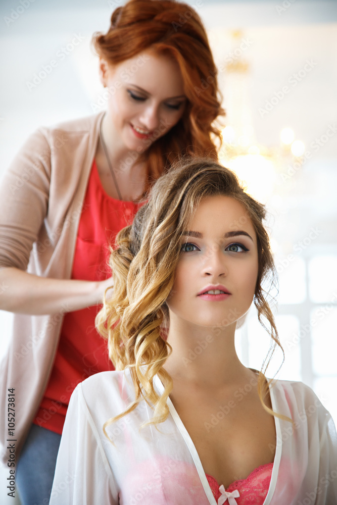 Hair Stylist preparing beautiful bride before the wedding in a morning
