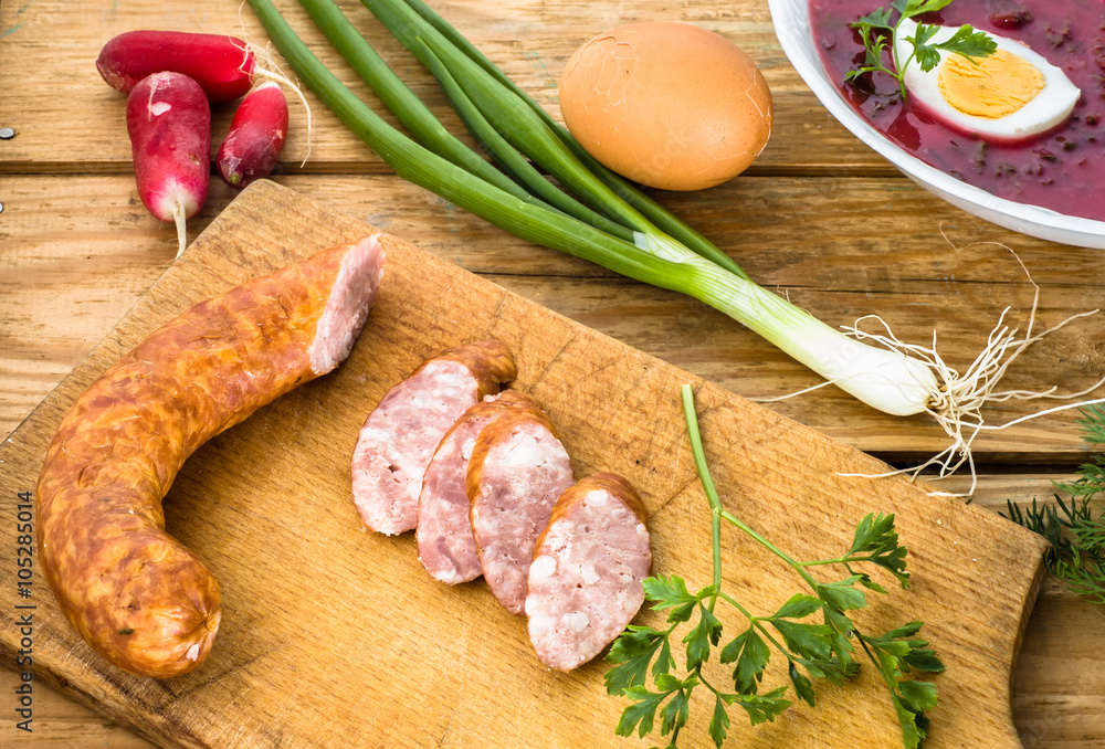 Sausage slices and borscht decorated with vegetables on wooden table Sausage slices and borscht decorated with vegetables on wooden table