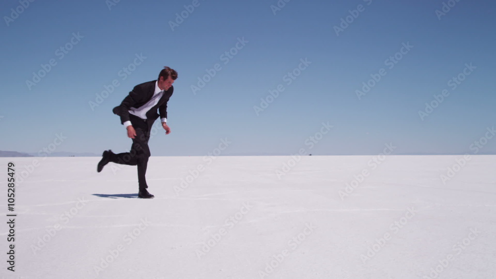 Businessman running at salt flat, slow motion Businessman running at salt flat, slow motion