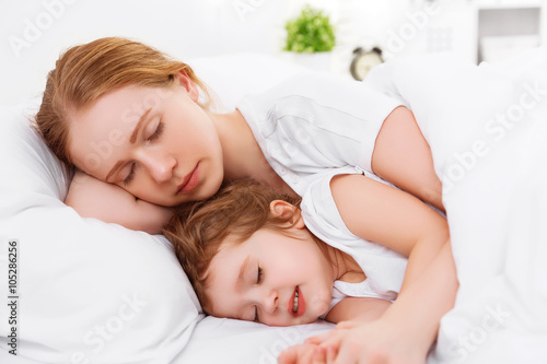 happy family mother and child sleeping in bed