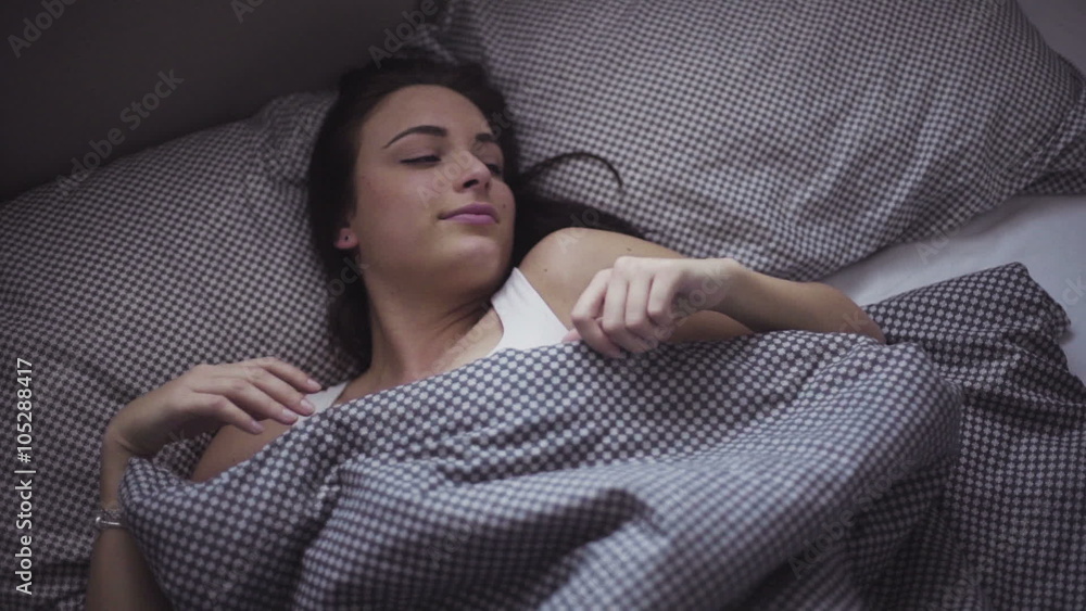 Female in her 20s wakes up in the morning in a bed, girl is stretching herself after sleeping. Female in her 20s wakes up in the morning in a bed, girl is stretching herself after sleeping.