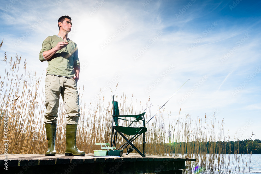 Naklejka premium Angler standing on jetty having food for breakfast