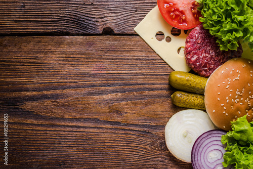 Ingredients for hamburgers on wooden table, border background