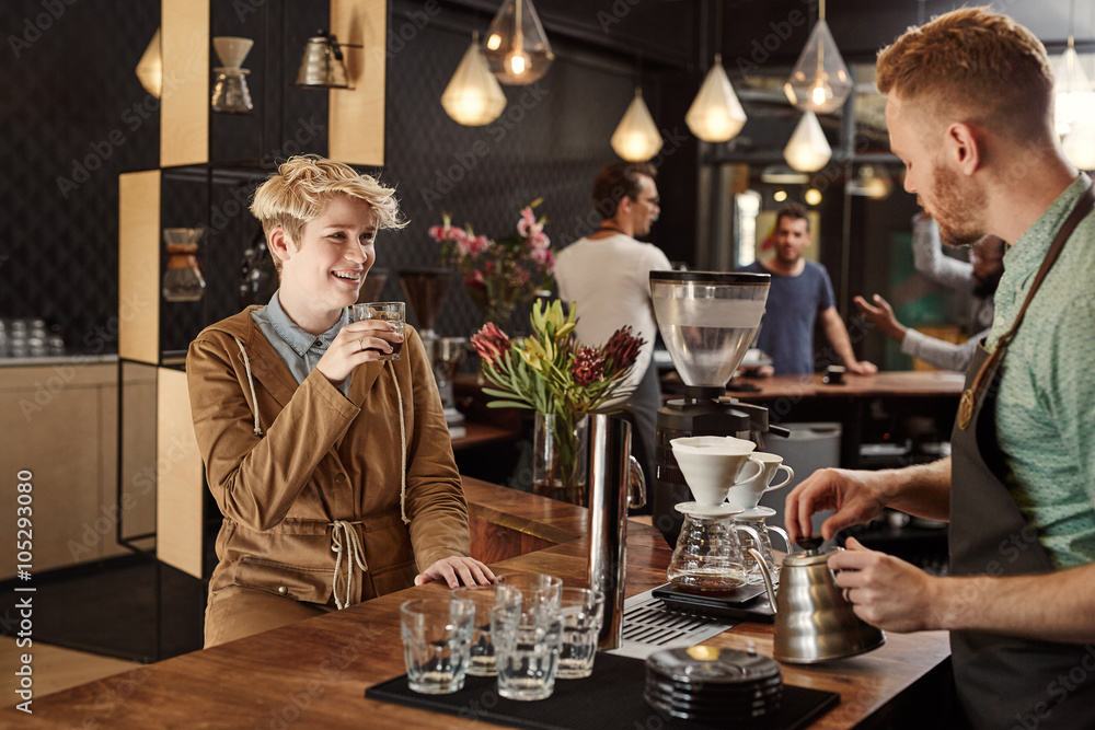 Young woman smiling while a barista makes some filter coffee