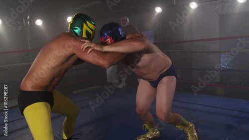 Masked wrestlers fighting in ring, slow motion photo