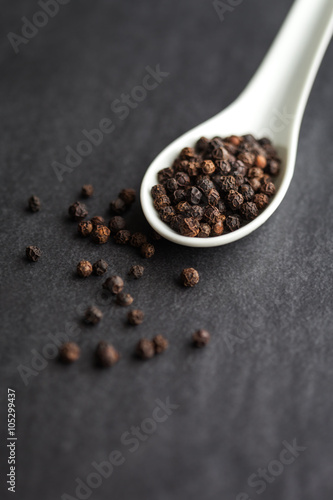 Peppercorns on white spoon with shallow depth of field