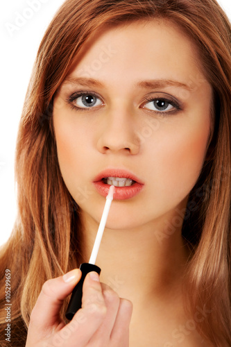 Teenage woman applying lip gloss