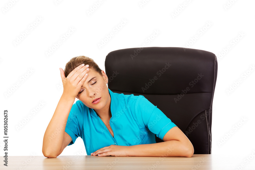 Tired young female doctoror nurse sitting behind the desk Tired young female doctoror nurse sitting behind the desk