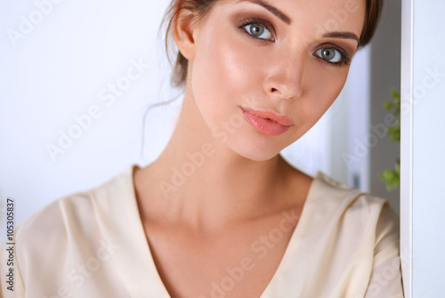 Attractive businesswoman standing near wall in office