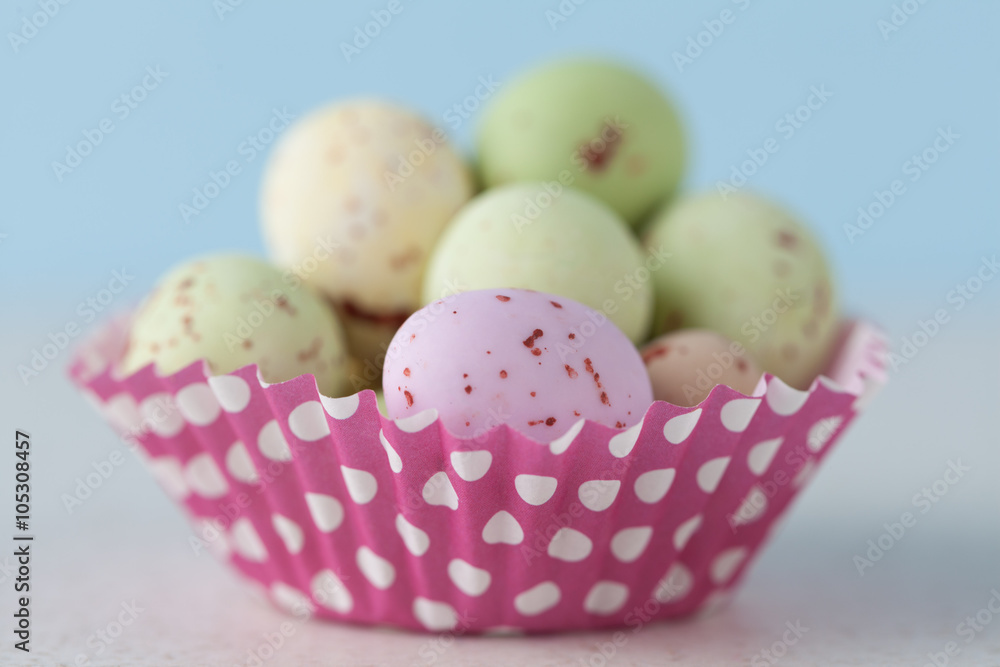 Extreme closeup of chocolate speckled Easter eggs in a crisp sugar shell in cupcape liner. Shallow depth of field.