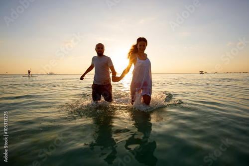 Romantic couple on the beach at colorful sunset on background